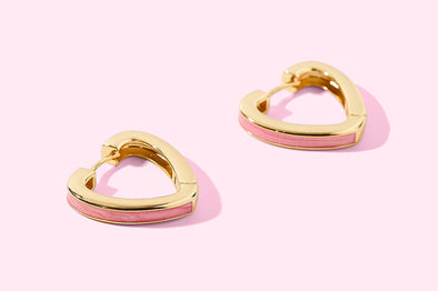 Gold and pink hoop earrings on a light pink background