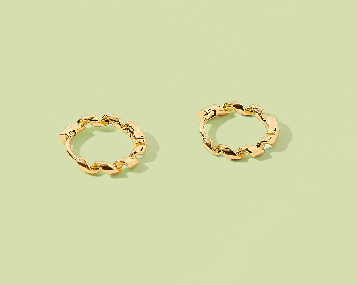 Pair of gold hoop earrings on a light green background